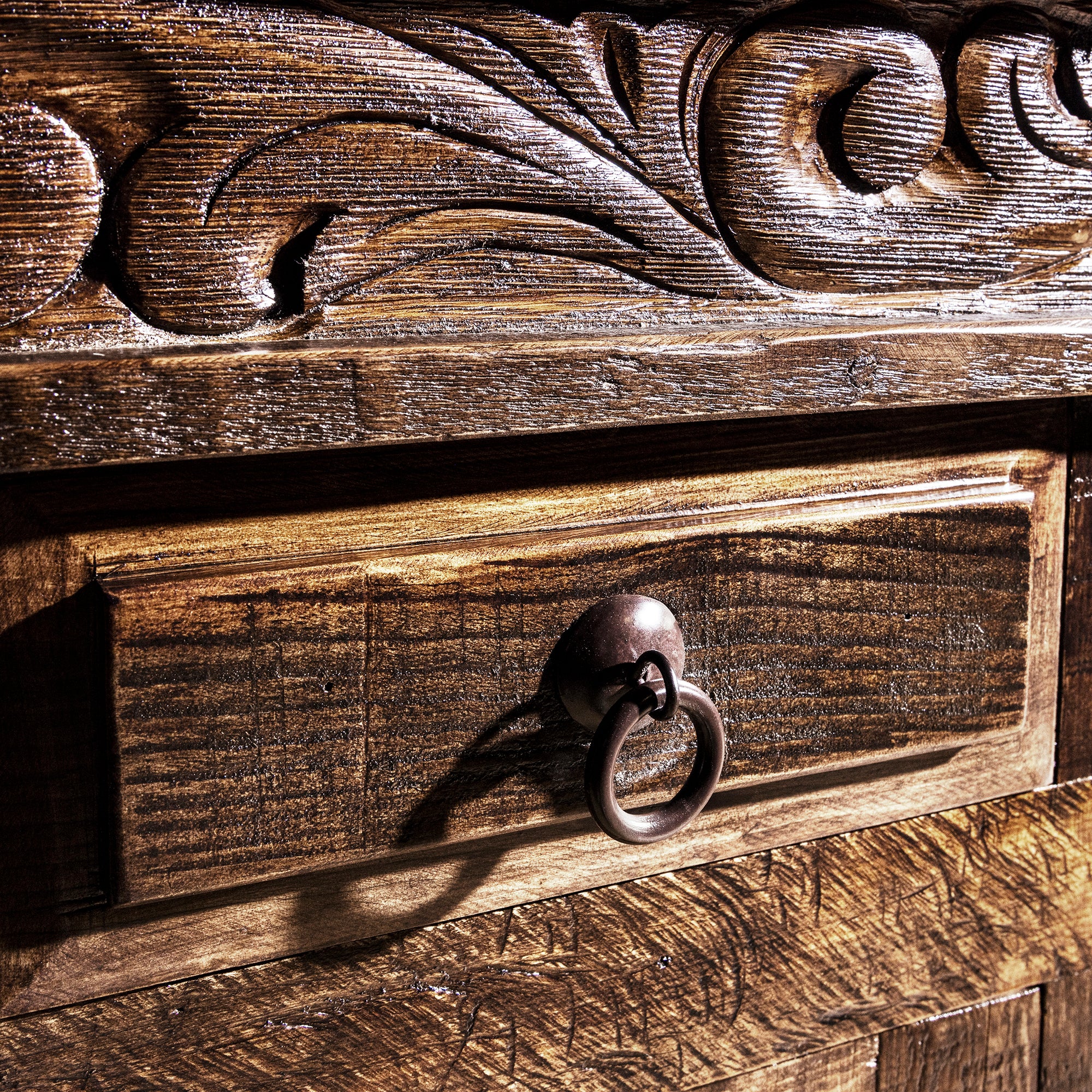 Ring-pull drawer hardware close-up on reclaimed wood carved Western buffet