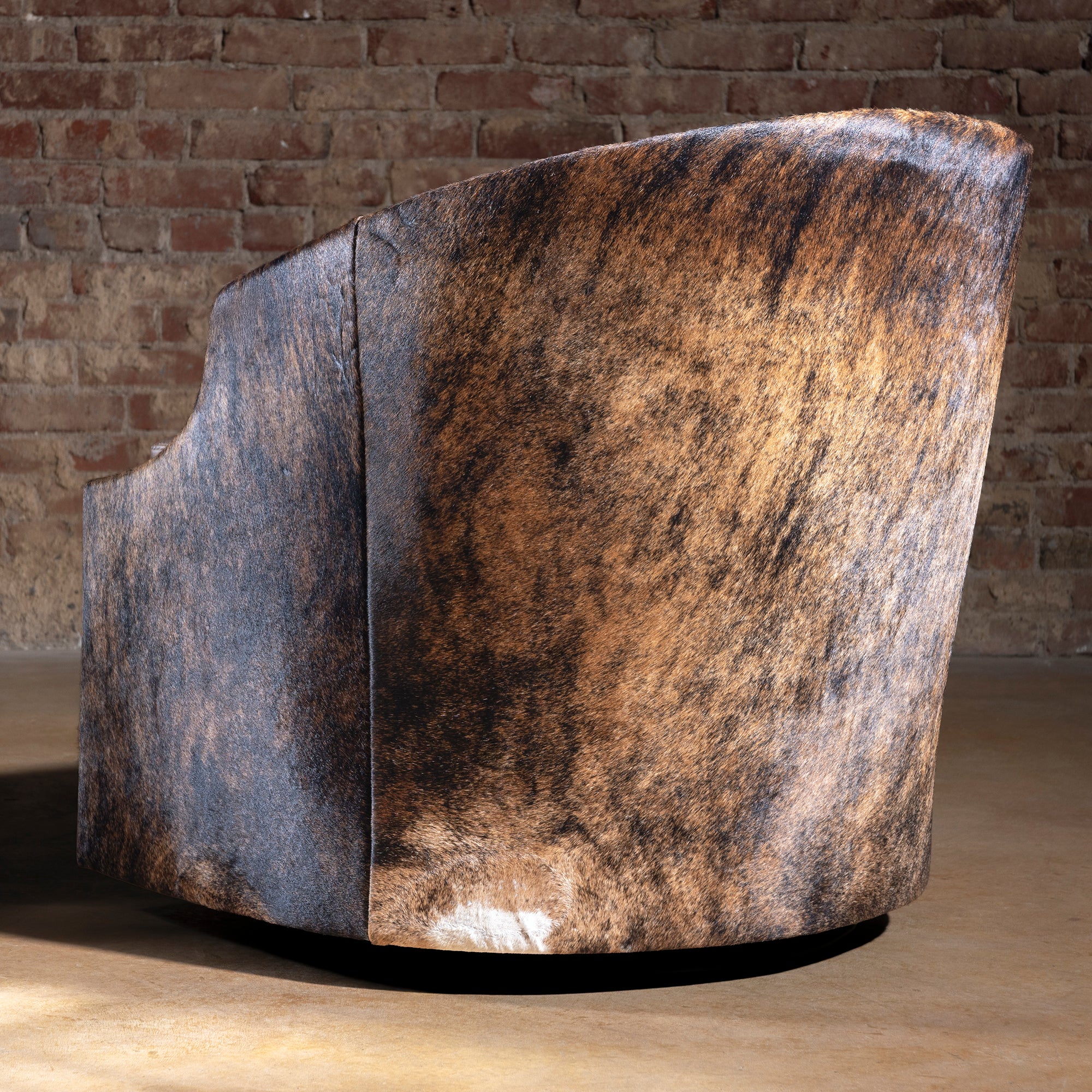 Back view of San Saba Bootstitch Swivel Chair showing brown cowhide and natural texture