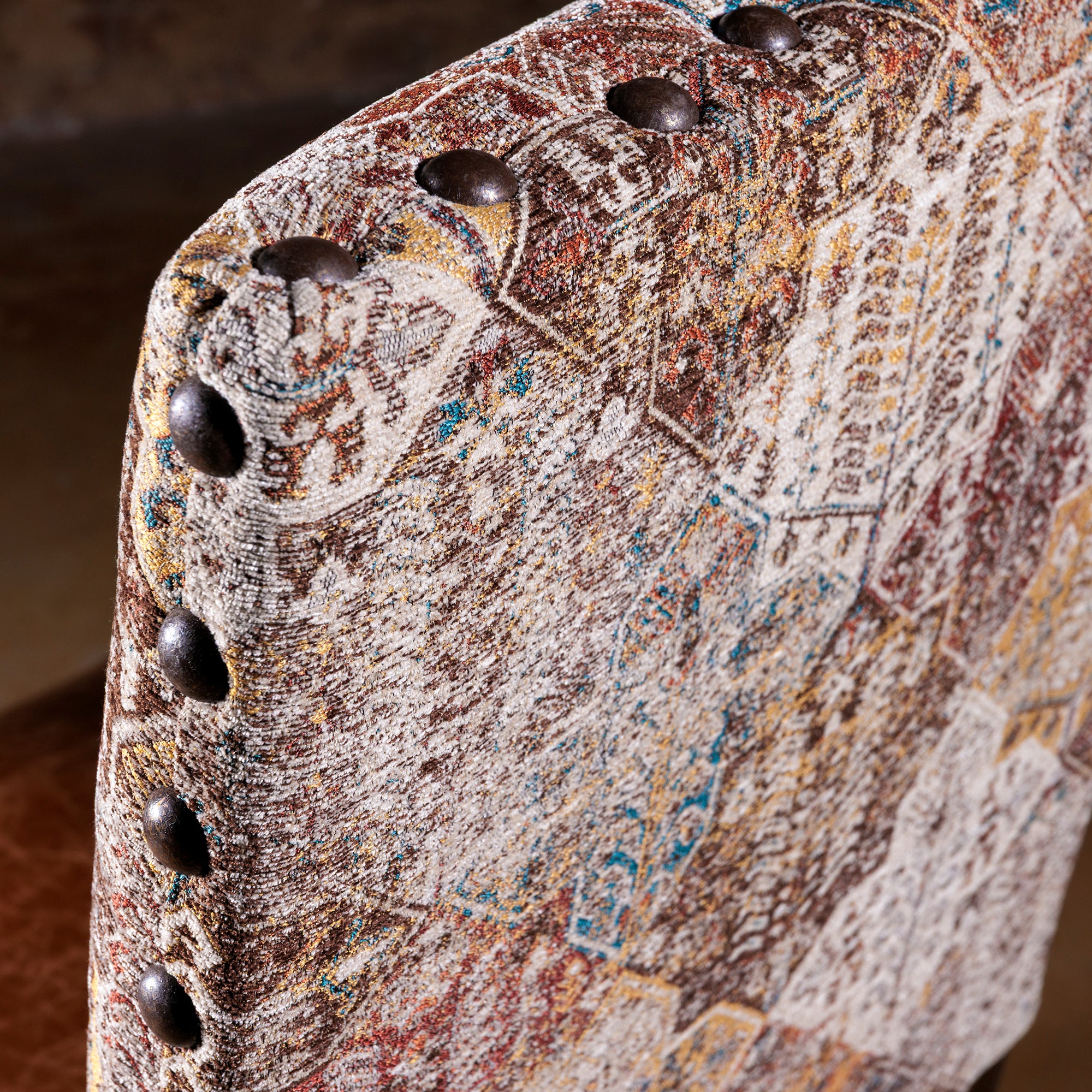 Close-up of antique-style nailhead trim and woven fabric on dining chair