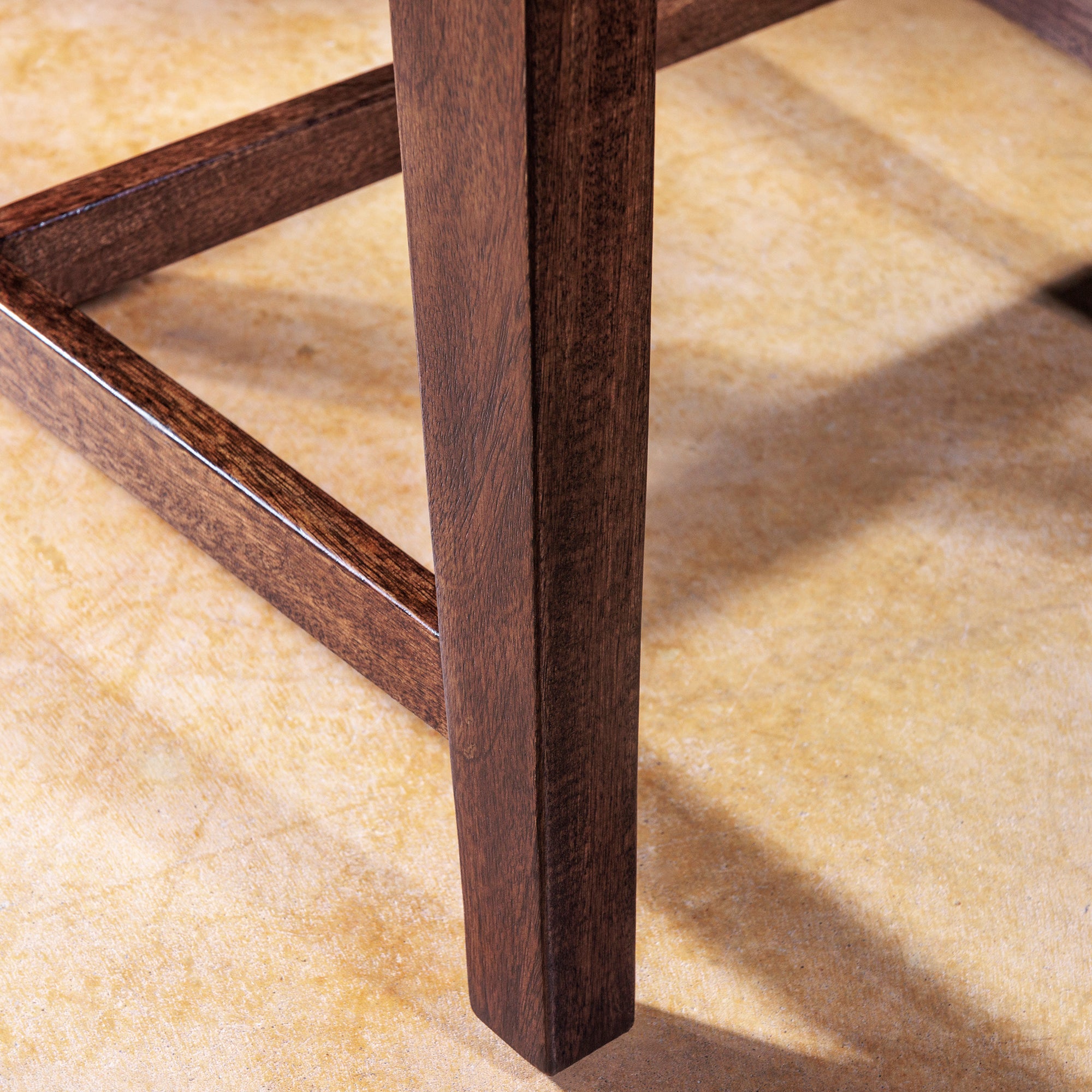 Detail of dark wood leg on handcrafted dining chair