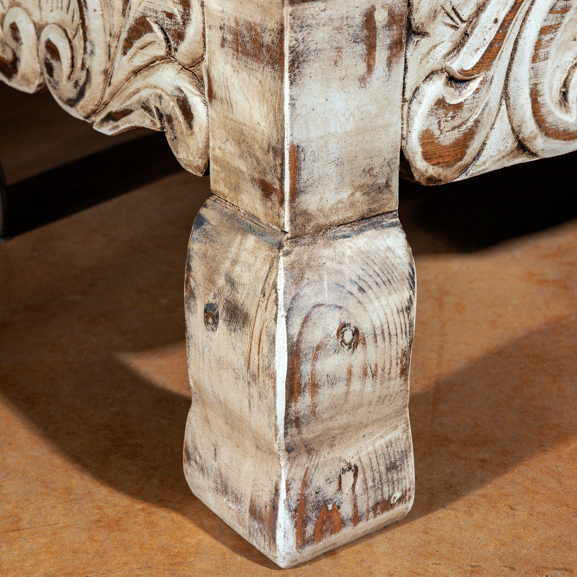 Close-up of carved console leg with distressed wood finish