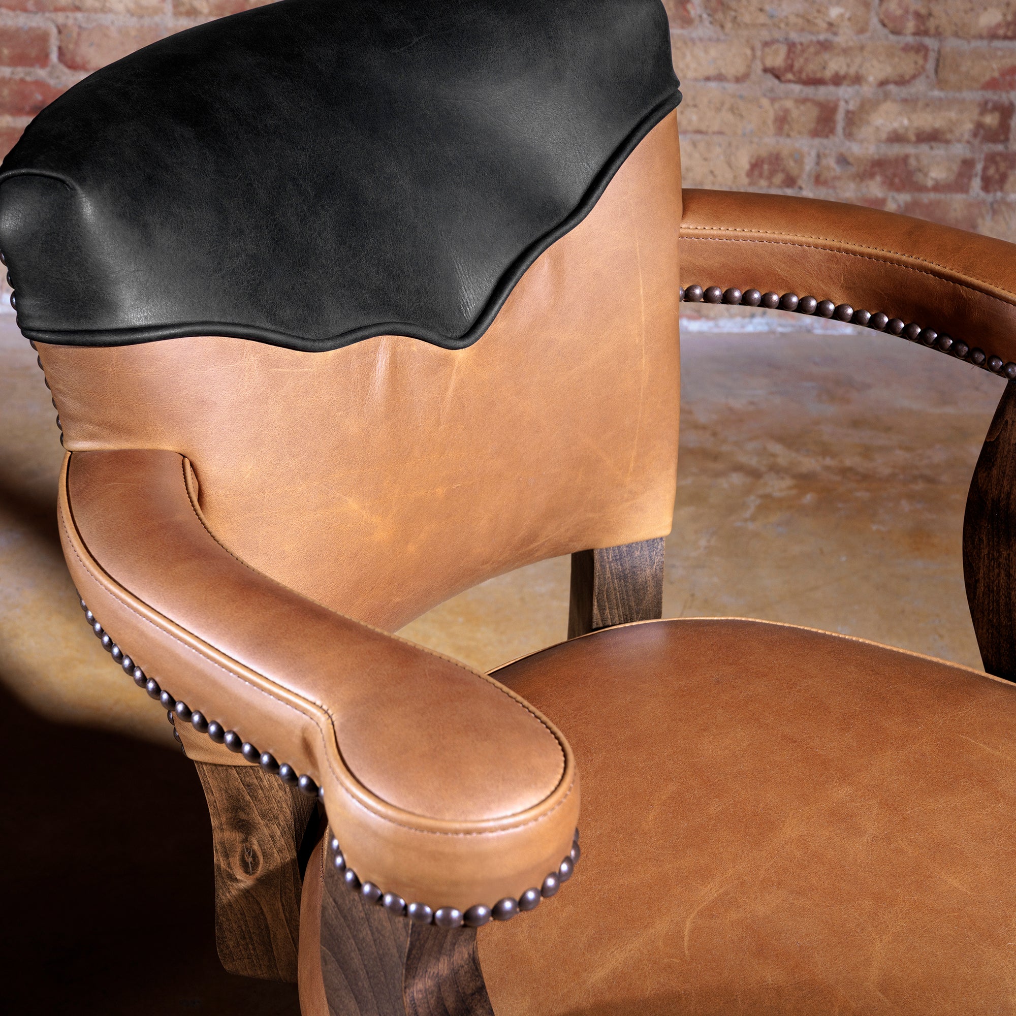 Detail shot of top-grain leather seat and curved armrest of The Santiago Swivel Bar Stool