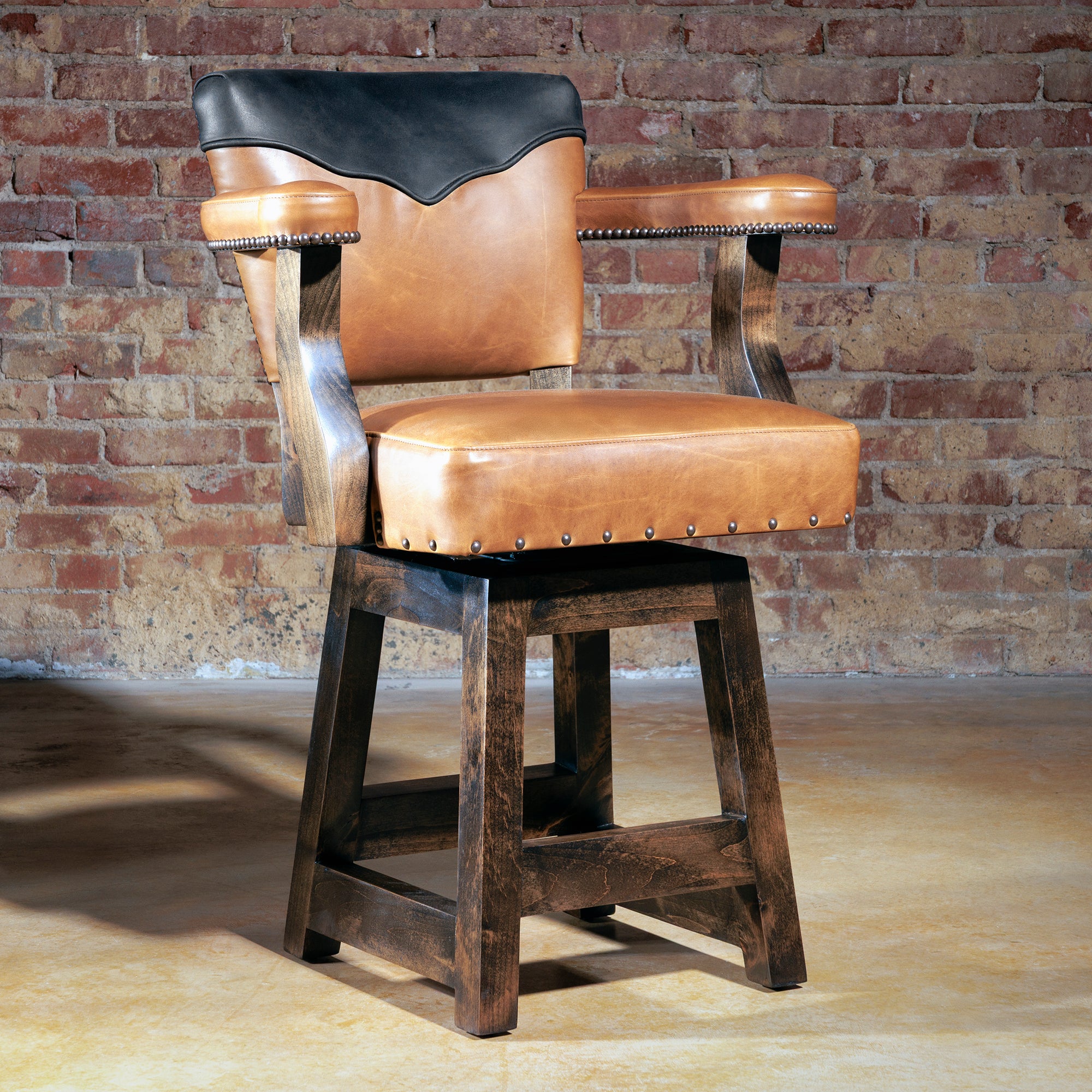 Front view of The Santiago Swivel Bar Stool in whiskey leather with midnight black yoke and nailhead trim
