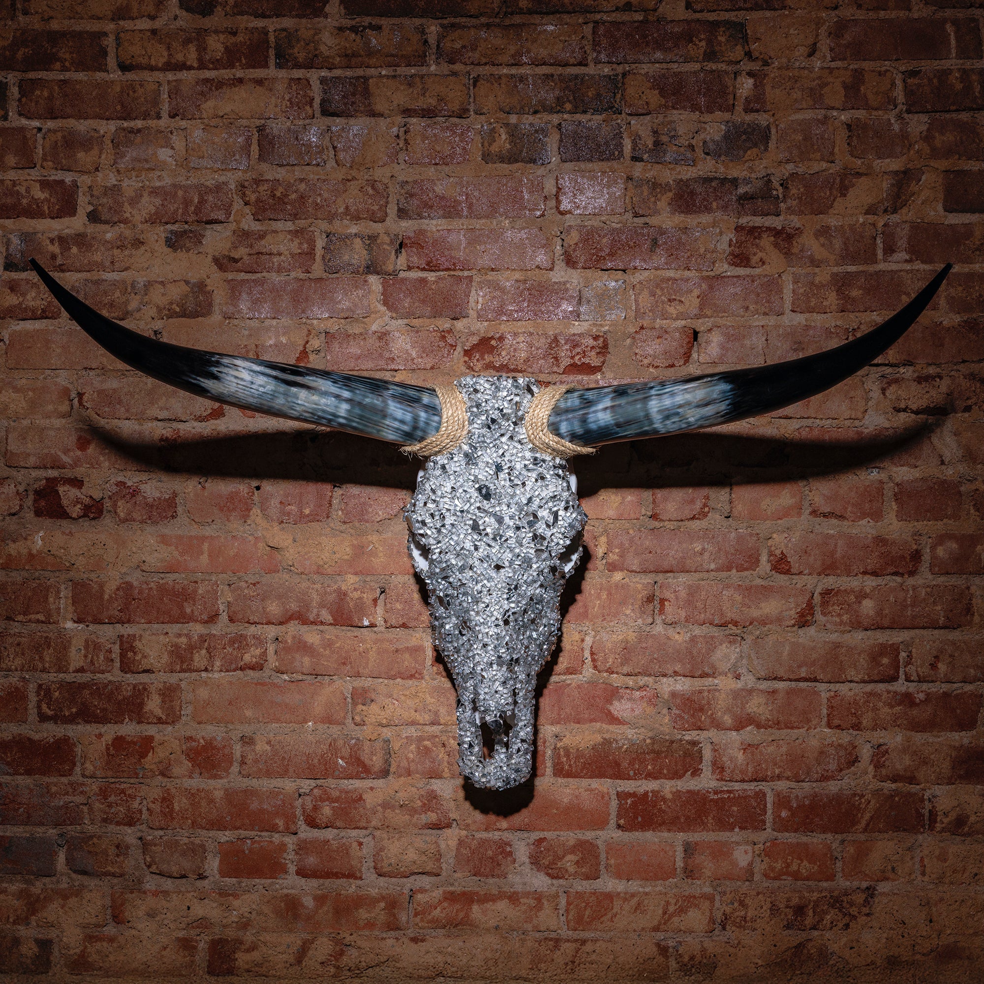 Silver crushed glass longhorn skull with wrapped horns mounted on brick wall