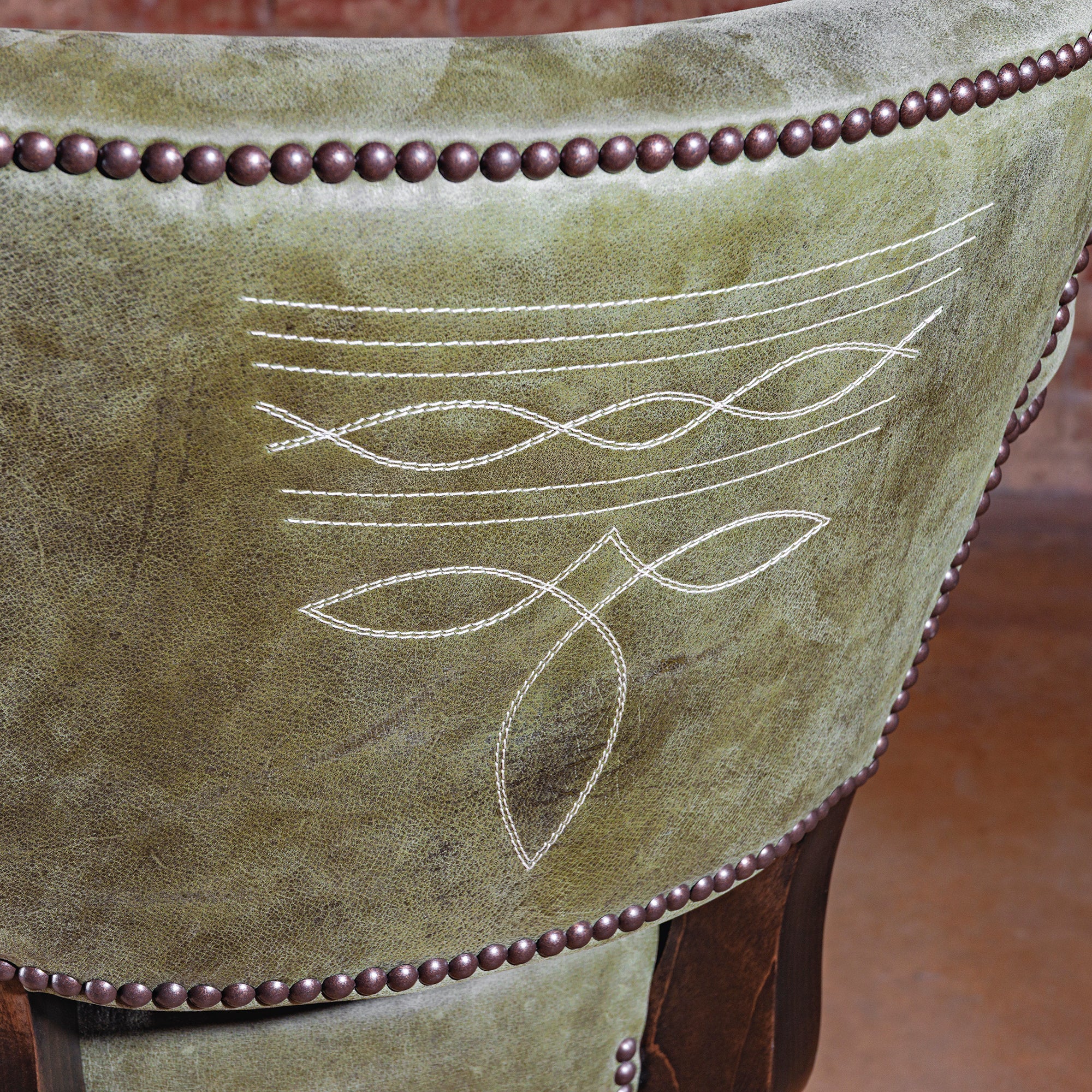 Close-up of boot-stitch embroidery on sage-green leather backrest—Sonora Verde