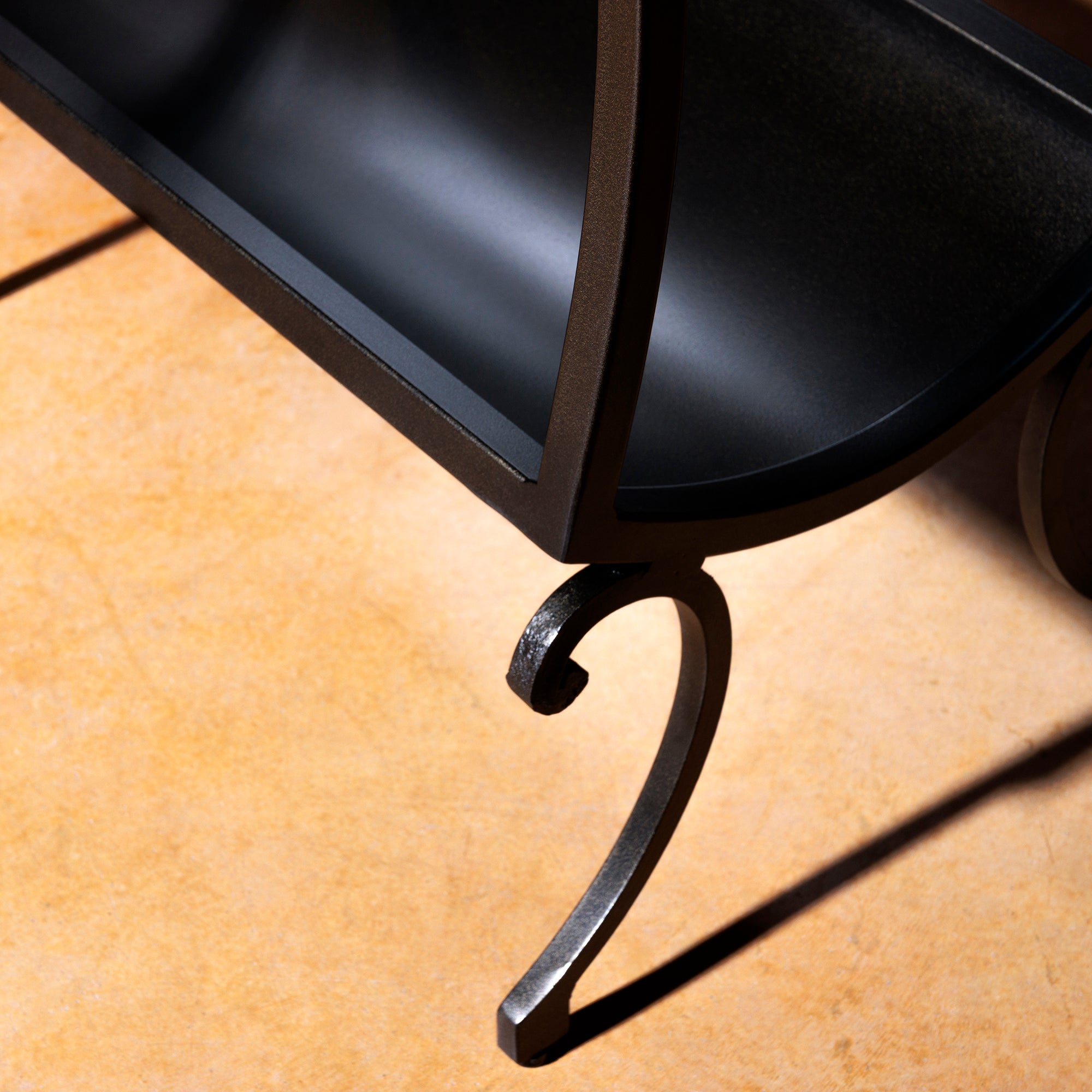 Wrought iron scroll leg detail on rustic copper table