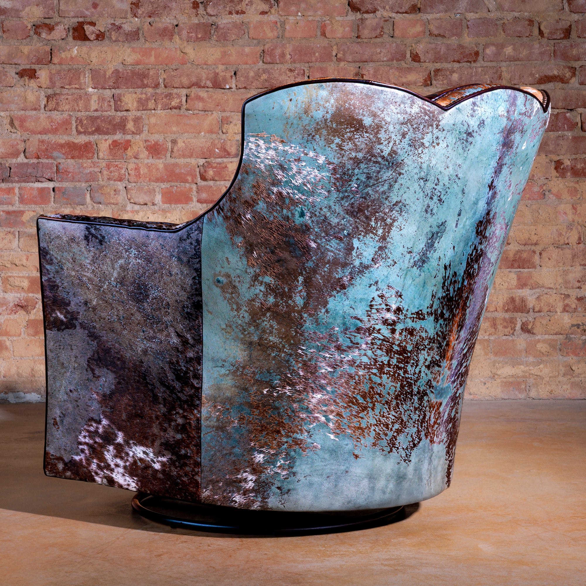 Back view of turquoise acid wash hide swivel chair showing unique cowhide pattern.
