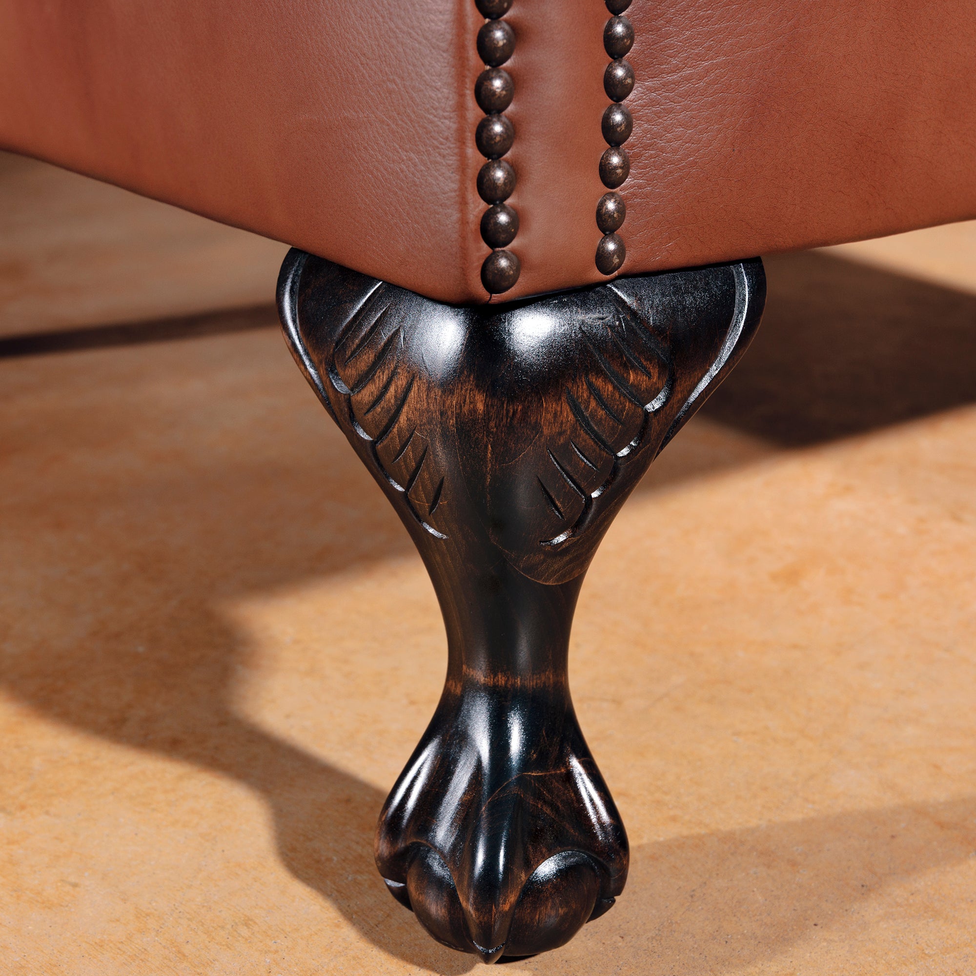 Carved clawfoot legs on Western leather wingback chair with rustic finish