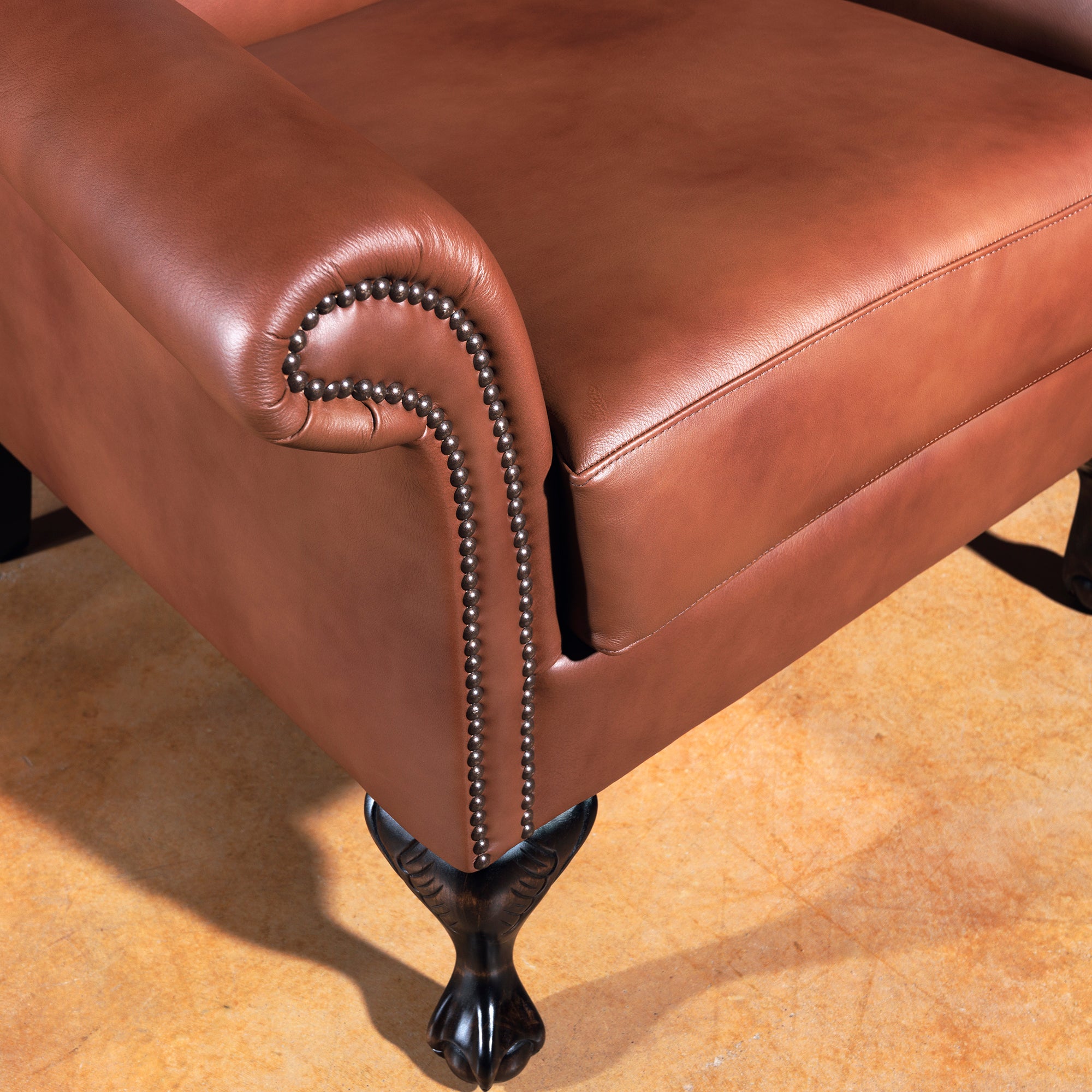 Rolled arm with bronze nailhead trim on Western leather wingback chair