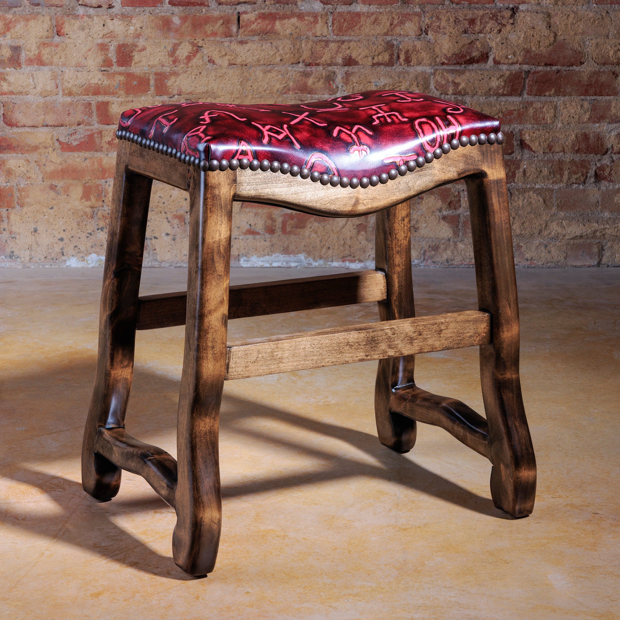 Western saddle-style stool with red branded leather seat and solid wood frame.