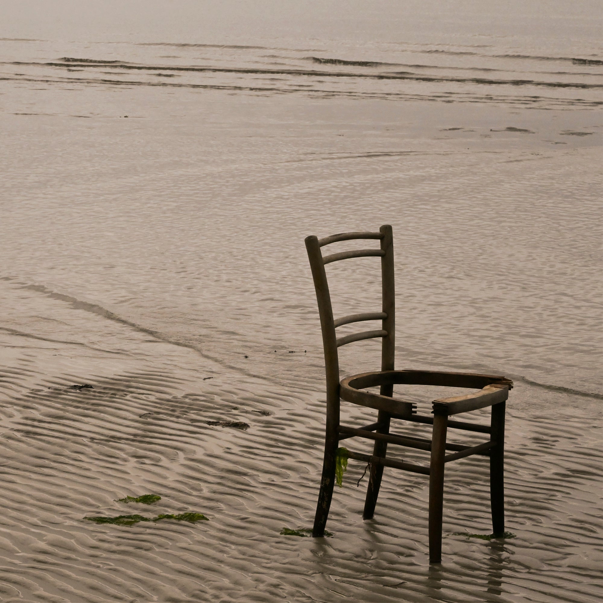 Old chair on a quiet beach with golden light and open sky