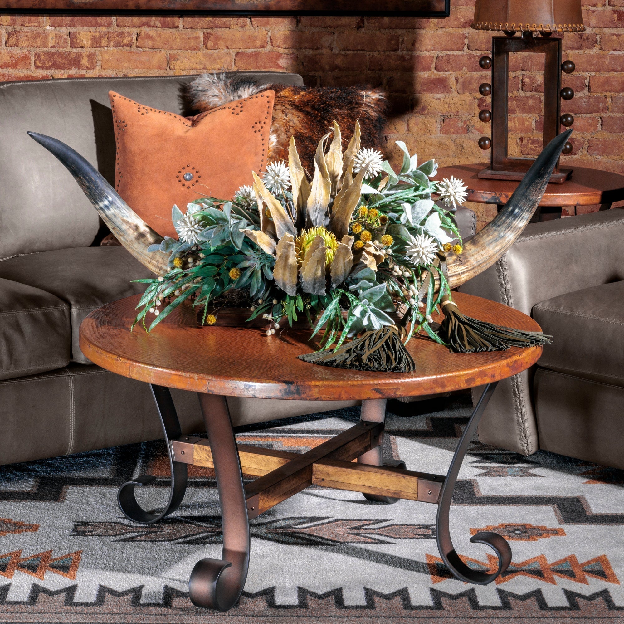 Western coffee table styled with hammered copper coffee table, and bullhorn floral in a rustic living room