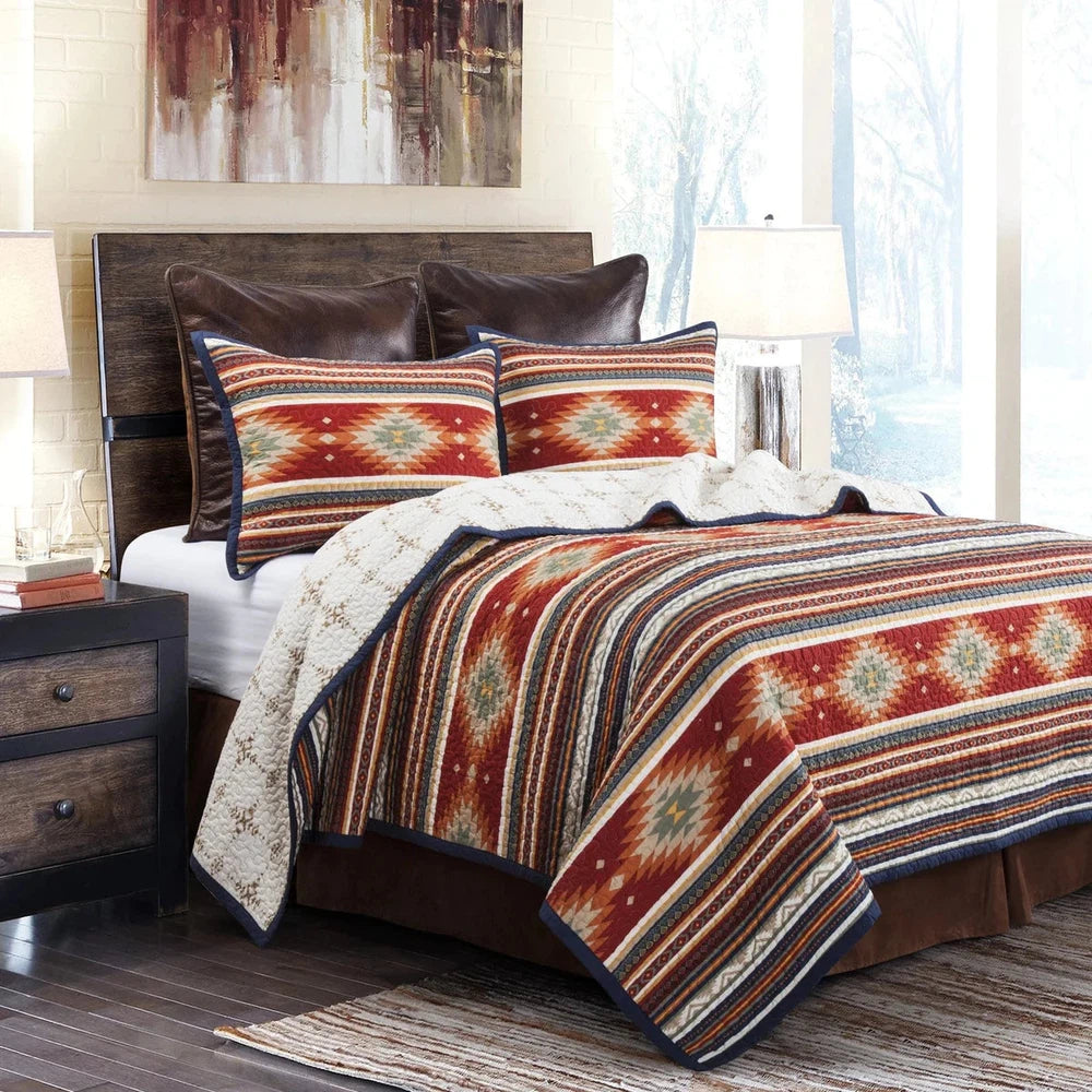 Transform your bedroom into a tranquil oasis with the Del Sol Quilt Set. This sophisticated modern twist on traditional Southwestern design features vibrant desert hues and superb Aztec-inspired patterns, framed by a navy flanged border for a bold, modern touch. Easily switch between two sides for added depth and a soothing, earthy look.