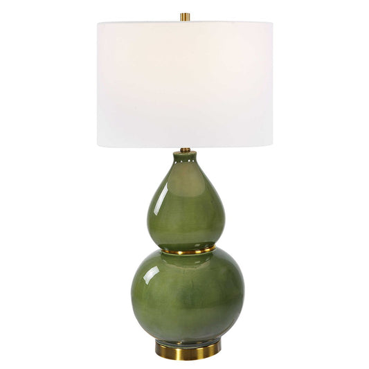 This Gourd Table Lamp is an elegant piece worthy of any home. Crafted with a timeless gourd shaped ceramic base, it features a moss green glaze accented with lightly antiqued brass plated details. The round drum shade is made from white linen fabric, giving the lamp a soft and inviting feel. Due to the unique nature of fired glazes on ceramic lamps, each lamp has an individual finish.