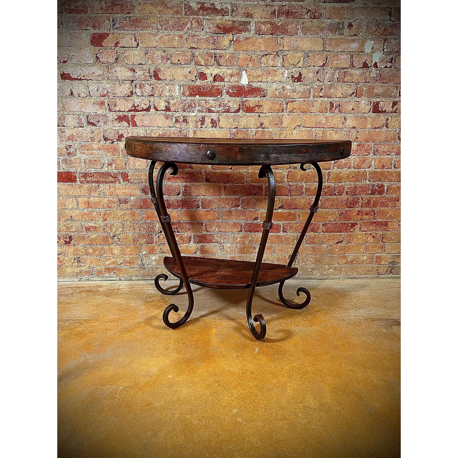 This Half Round Table is expertly crafted with a hand forged iron base, providing exceptional durability and a unique design. Its solid wood top adds a touch of natural beauty, while the wood shelf at the bottom offers additional storage space. A perfect choice for both style and function.