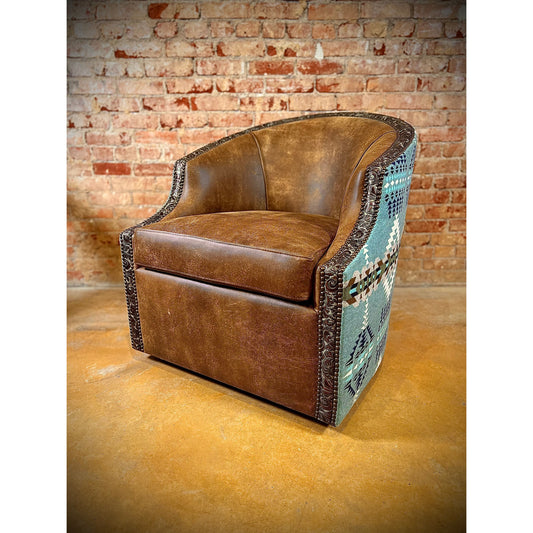 This Rancho Arroyo Shale Barrel Chair offers a luxurious seating experience with its swivel design upholstered with top grain leather and stamped leather trim. The ornamental Pendleton fabric adds an elegant touch. Perfect for modern or ranch house living rooms.