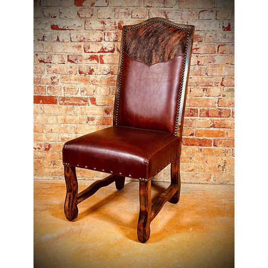 Add a touch of western elegance to your dining room with our Leather &amp; Cowhide Yoke Dining Chairs. These chairs feature top grain leather and brindle cowhide for a luxurious look. The nailhead accents and wood trim add a touch of sophistication. Crafted with solid wood, these chairs are both stylish and durable. Elevate your dining experience with these unique dining chairs.