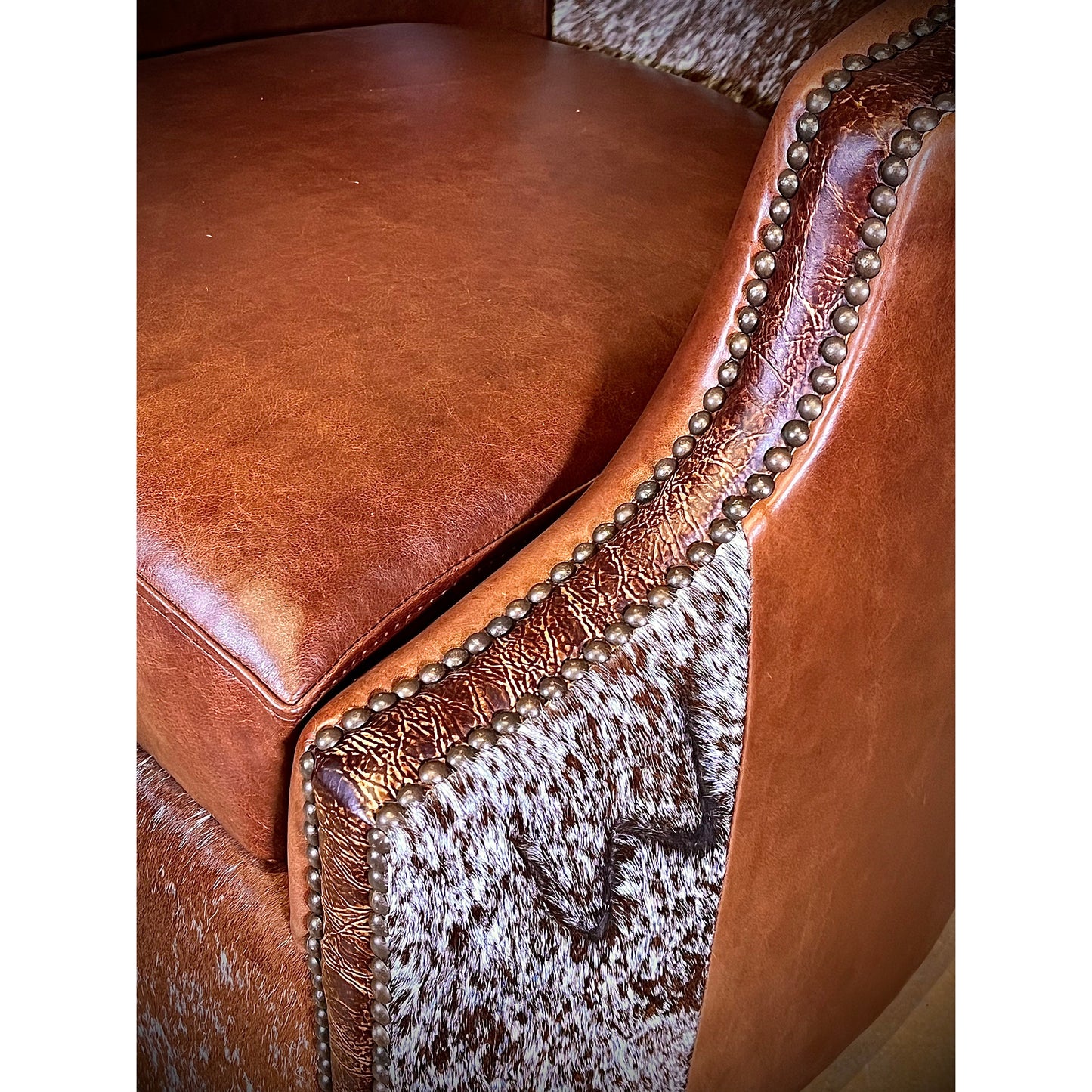 Experience ultimate comfort in style with the Longhorn Swivel Leather Barrel Chair. Made with top grain leather and hair on hide accents, this chair boasts a western flair with its nailhead trim and 360 degree swivel feature. Get ready to relax in extreme comfort and add a touch of rustic charm to your space!