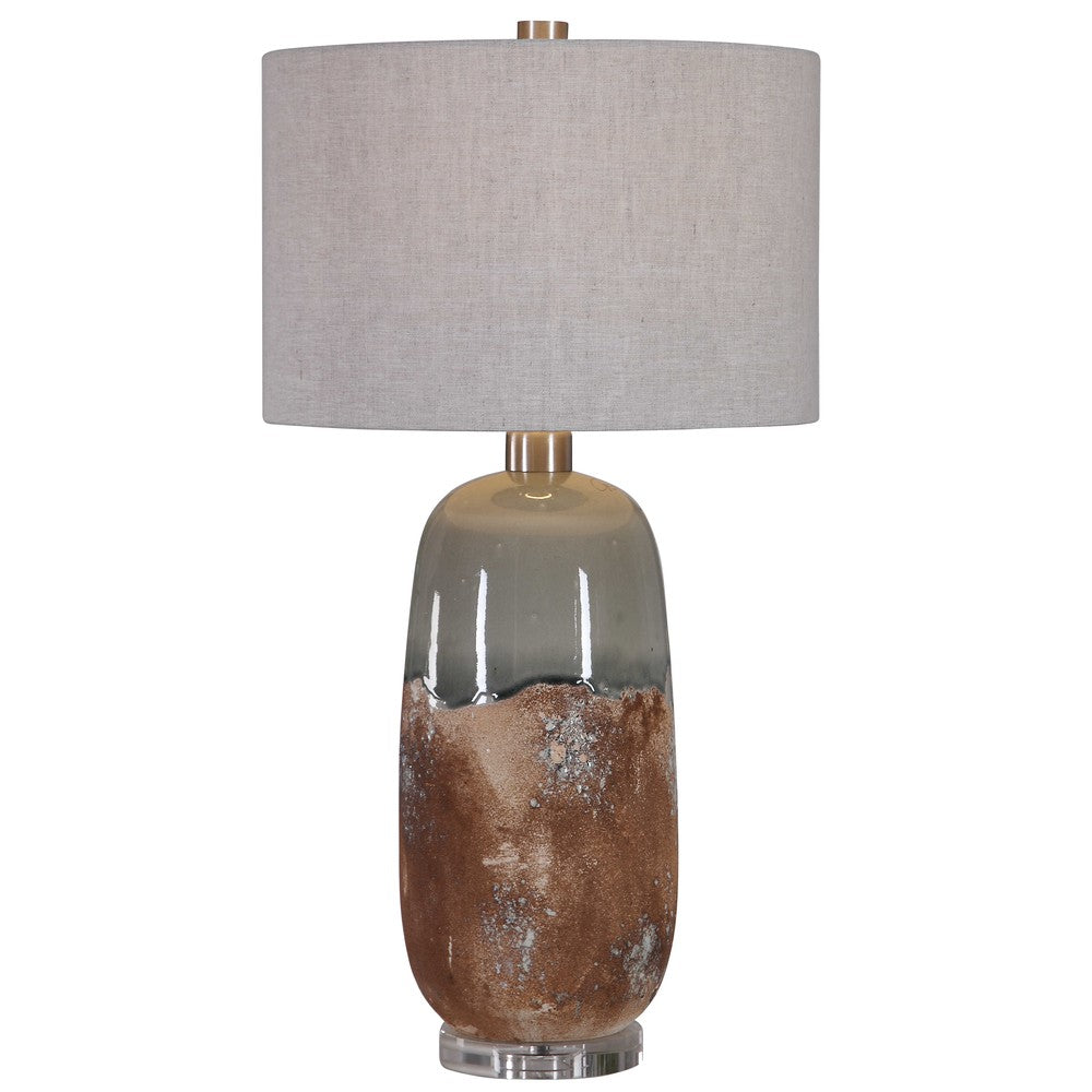 The Maggie Table Lamp's unique ceramic base features a terracotta rust finish with a crackled green-gray glaze, complemented by brushed nickel details and a thick crystal foot. The warm gray linen shade, with natural slubbing, provides a subtle yet stylish lighting effect to any room.