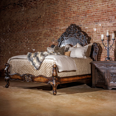 Romantic western bed with curved carved headboard and antiqued wood finish in an intimate bedroom