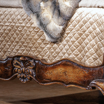 Romantic western bed with curved carved headboard and antiqued wood finish in an intimate bedroom