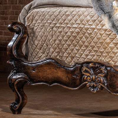 Romantic western bed with curved carved headboard and antiqued wood finish in an intimate bedroom