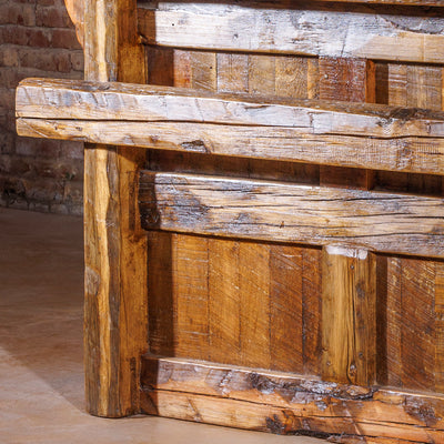 Classic rustic western bed frame with arched wood headboard and footboard in a cozy ranch bedroom