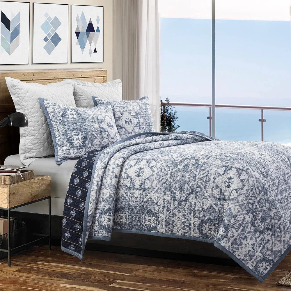 Gently mimic the natural pattern of ocean waves and bring a sense of serenity to your bedroom with the Skyler Quilt Set. Crafted using traditional shibori dyeing techniques to reflect the beauty of the sea, the ornate front reverses to a navy backdrop decorated with golden stripes and medallions. Create a coastal, rustic, or land-meets-sea look with neutral airy or taupe and tan accents.