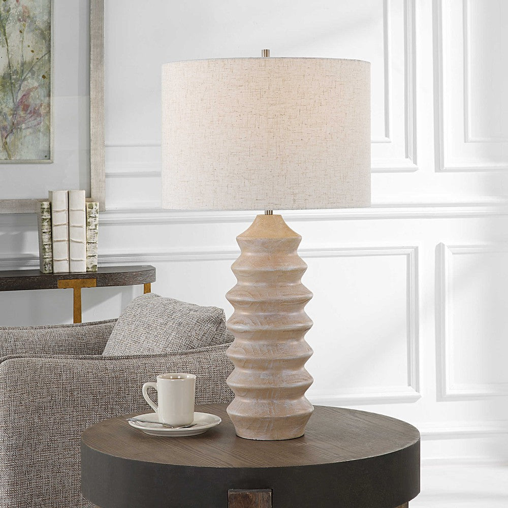 Make a bright statement in your home with the Uplift Table Lamp. It features a carved geometric base in a bleached wood tone look with nickel plated iron details. This modern lamp is finished with a casual oatmeal linen slubbed drum shade, creating a stunning aesthetic
