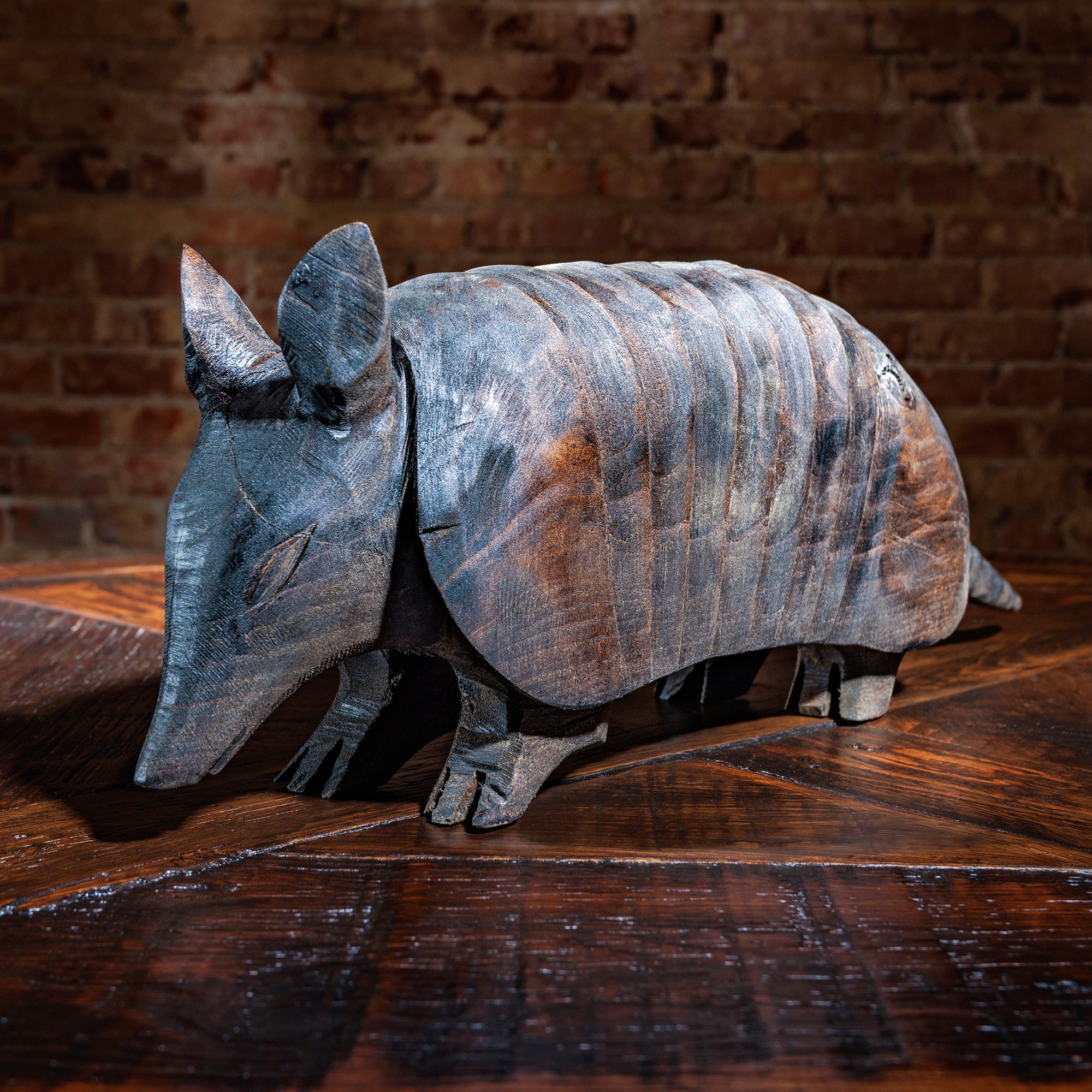 Hand-carved wooden armadillo facing forward on rustic wood table