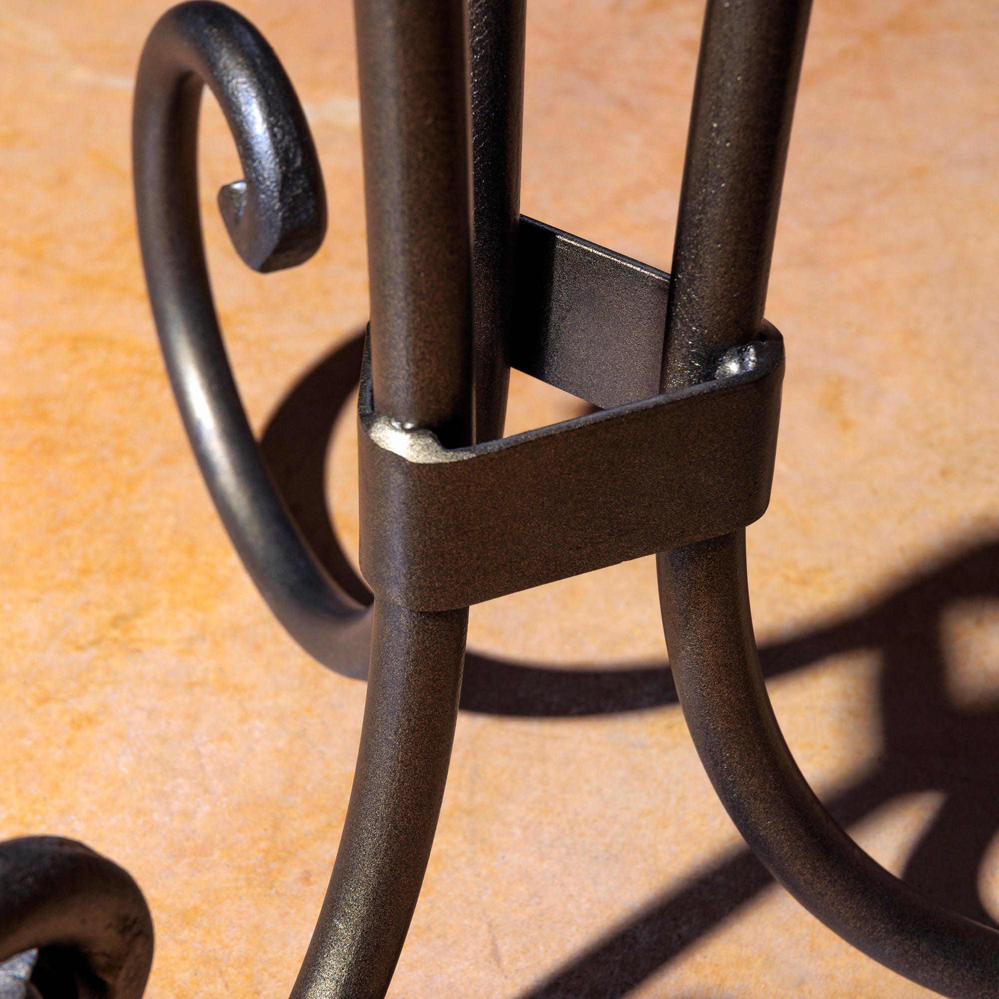 Close-up of scroll-shaped wrought iron base on The Azul Mesa Accent Table