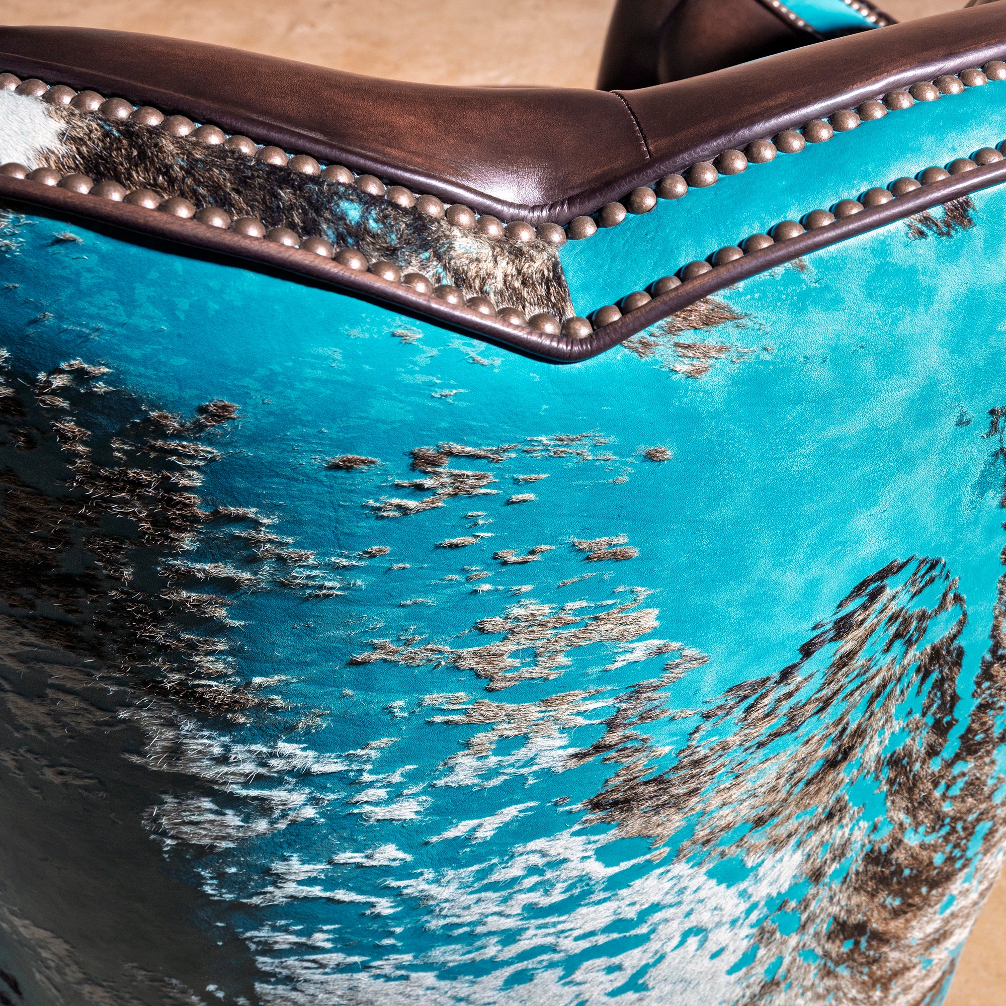 Azure Spur Tufted Western Swivel Chair western swivel chair nailhead detail with turquoise cowhide and leather-wrapped upper edge.