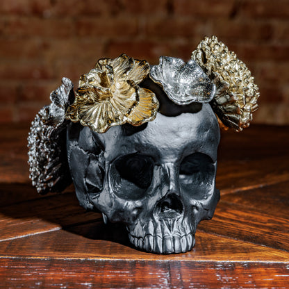 Black skull sculpture with metallic floral crown on rustic wood surface