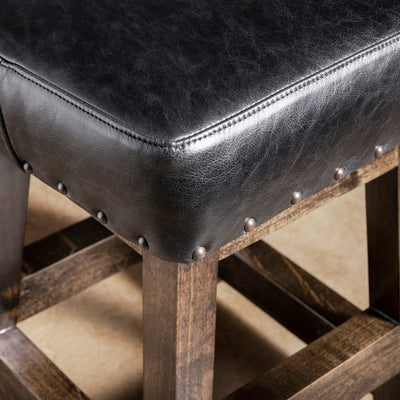 Close-up of black leather bar stool seat with nailhead trim and dark stained alder wood frame—Western counter or bar seating