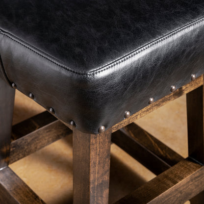 Close-up of black leather bar stool seat with nailhead trim and dark stained alder wood frame—Western counter or bar seating