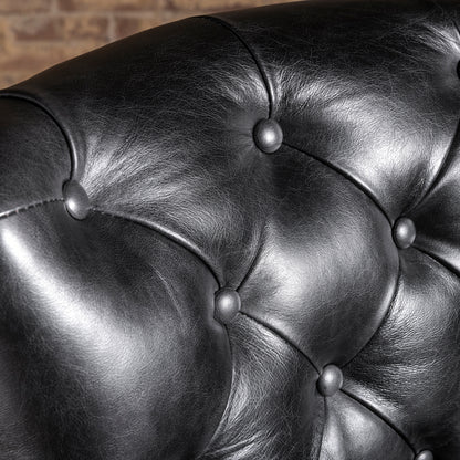 Close-up of button-tufted black leather backrest on Western bar stool—tailored leather upholstery detail for ranch home bar