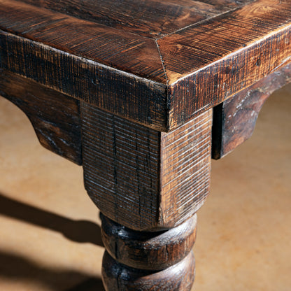 Closeup of reclaimed wood pub table corner showing thick top and turned leg.