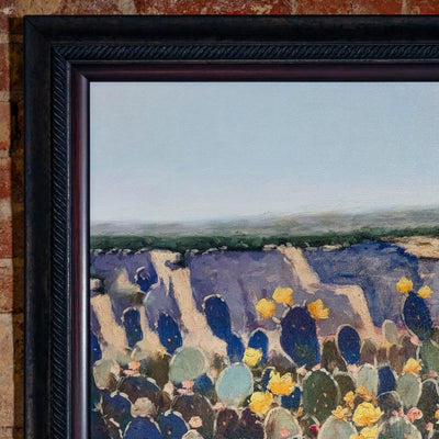 Close-up of textured cactus flowers and painted desert in ornate Western frame