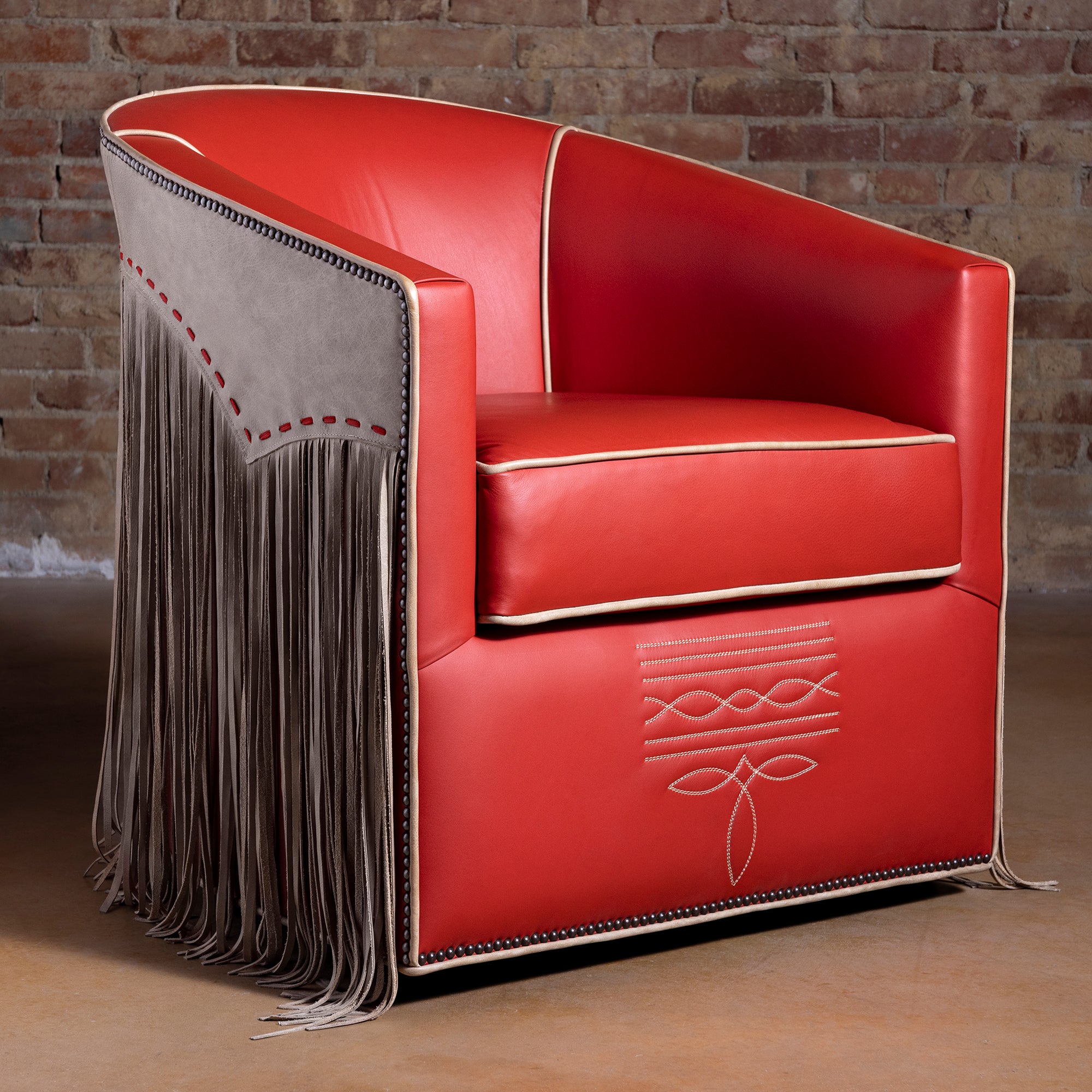 Coral-red leather Western swivel chair with fringe, nailhead trim, and cream piping