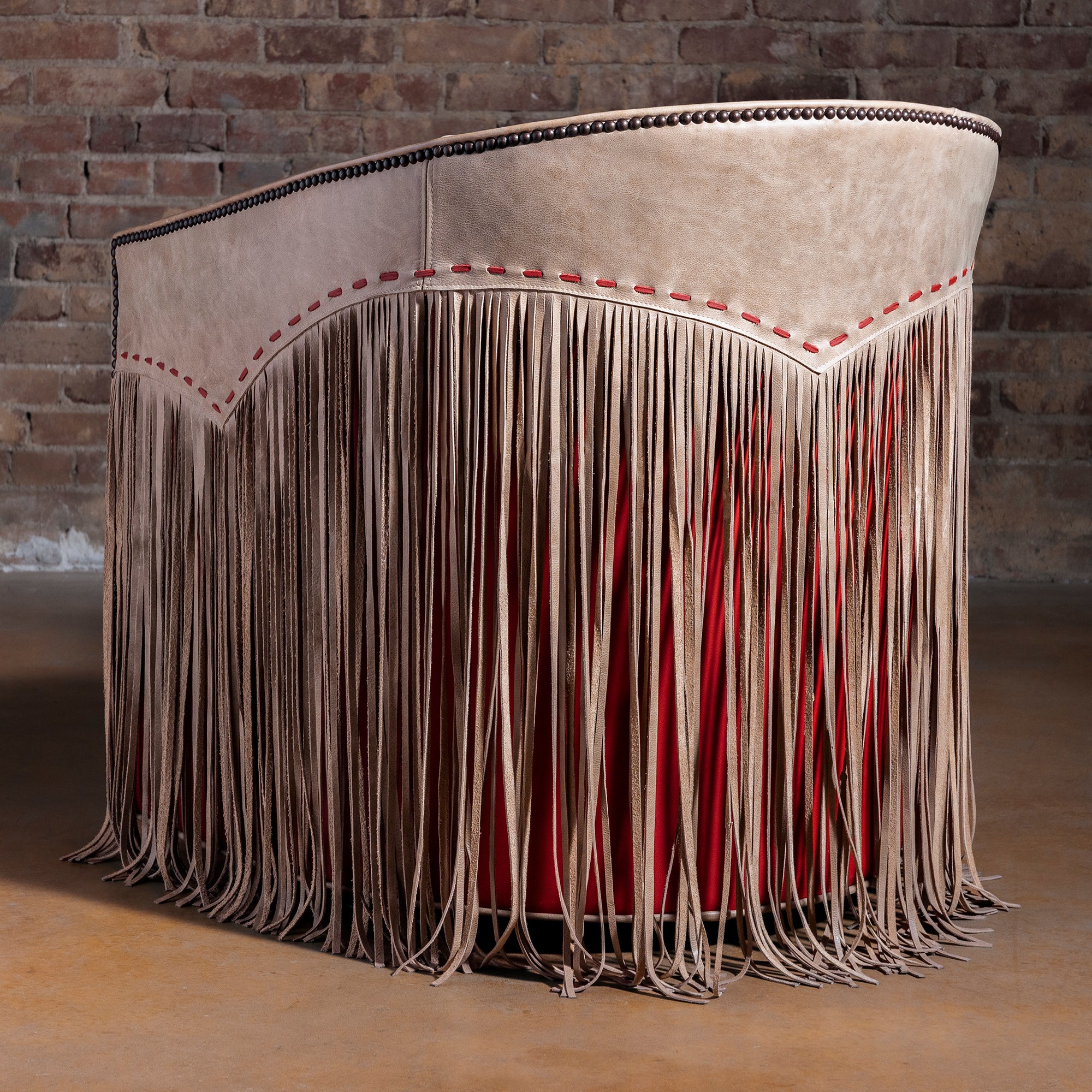 Back view showing taupe leather panel, red lacing, and full fringe on swivel chair