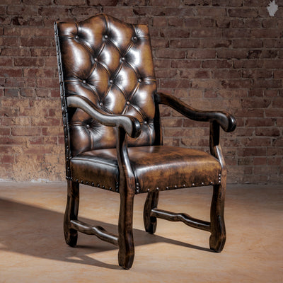 High-back tufted brown leather Western arm chair with nailhead trim and ranch-finished wood frame—host chair style.