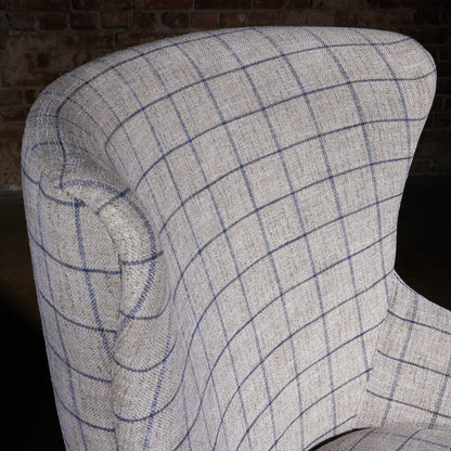 Close-up of windowpane plaid fabric on curved high back, upscale western accent chair upholstery texture