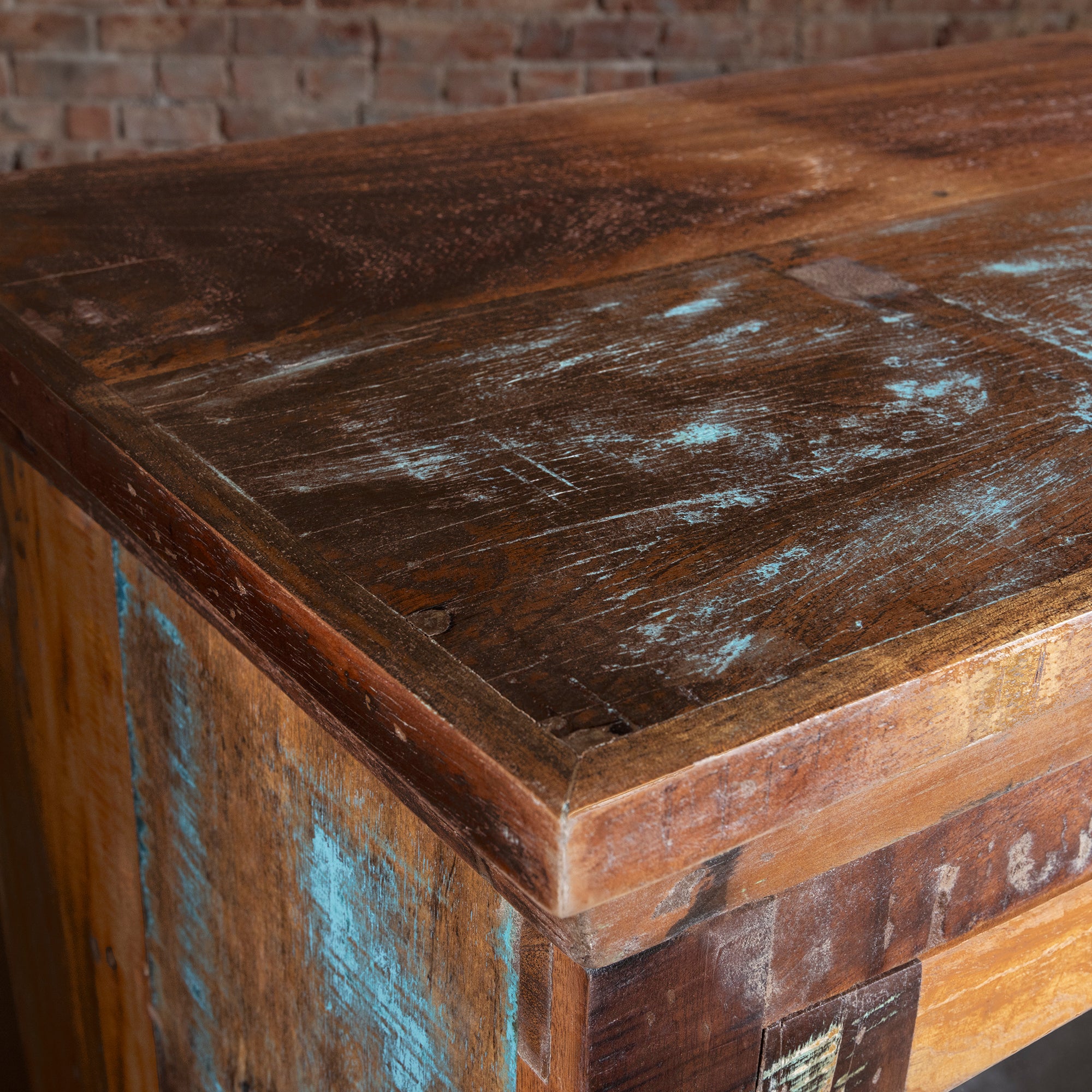 Corner close-up of reclaimed wood buffet top showing distressed turquoise accents, luxury Western furniture detail