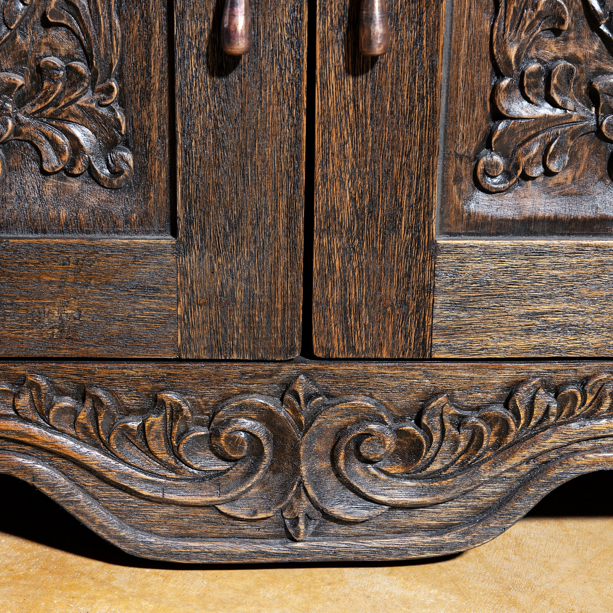 Hand-carved scrollwork base detail on rustic Western nightstand with dark walnut patina and textured grain
