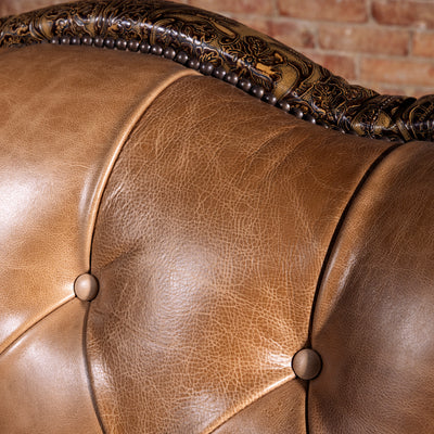 Close-up of saddle-toned top-grain leather texture on tufted Western sofa