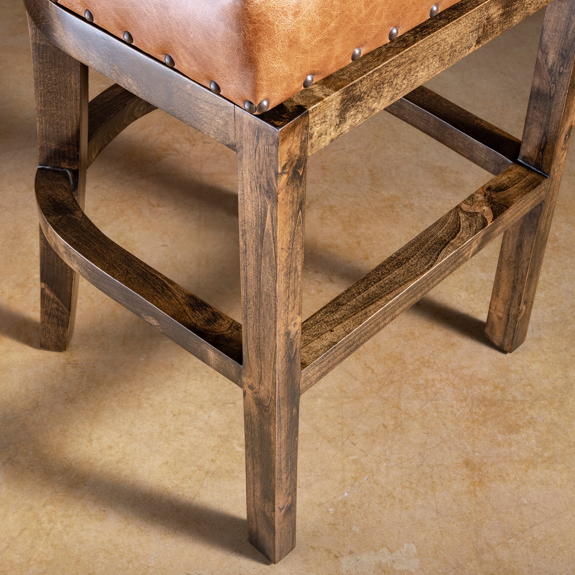 Frame detail of Catalina leather bar stool showing solid wood base, stretchers, and sturdy footrest