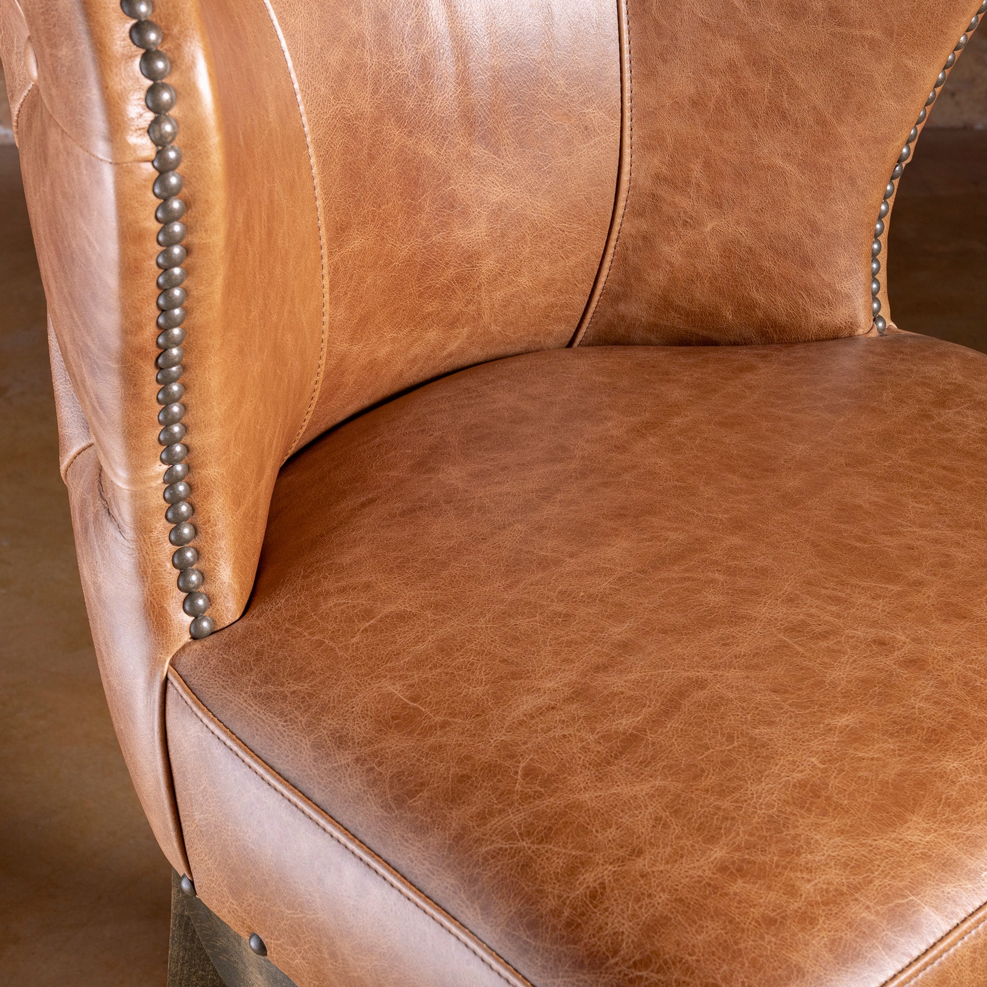 Detail of Catalina bar stool seat and curved back showing leather paneling and refined silhouette
