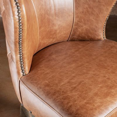 Detail of Catalina bar stool seat and curved back showing leather paneling and refined silhouette