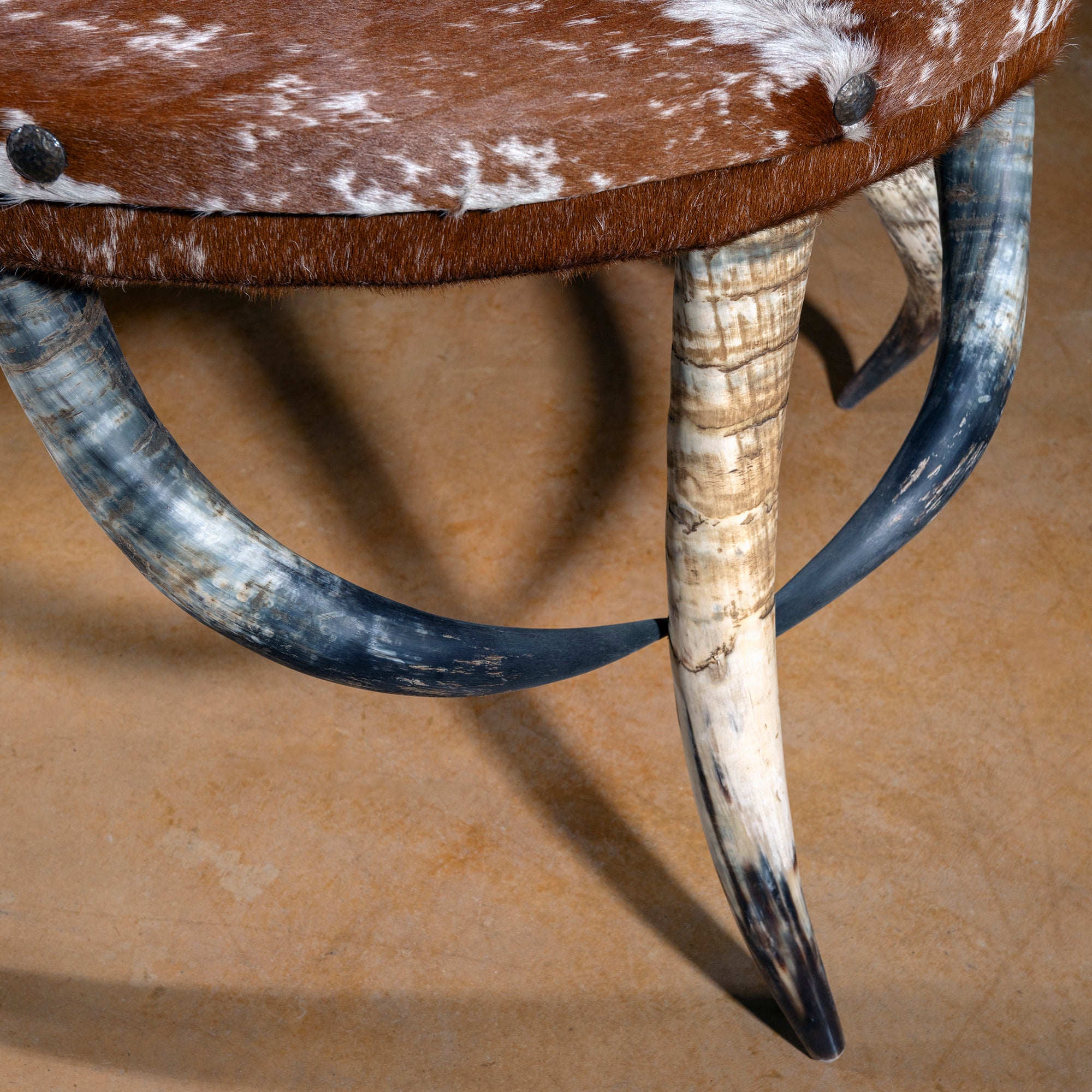 Detail of curved bullhorn legs supporting half-moon cowhide Western accent table