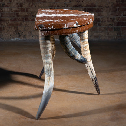 Profile view of demi-lune cowhide accent table showing horn legs and arched stance